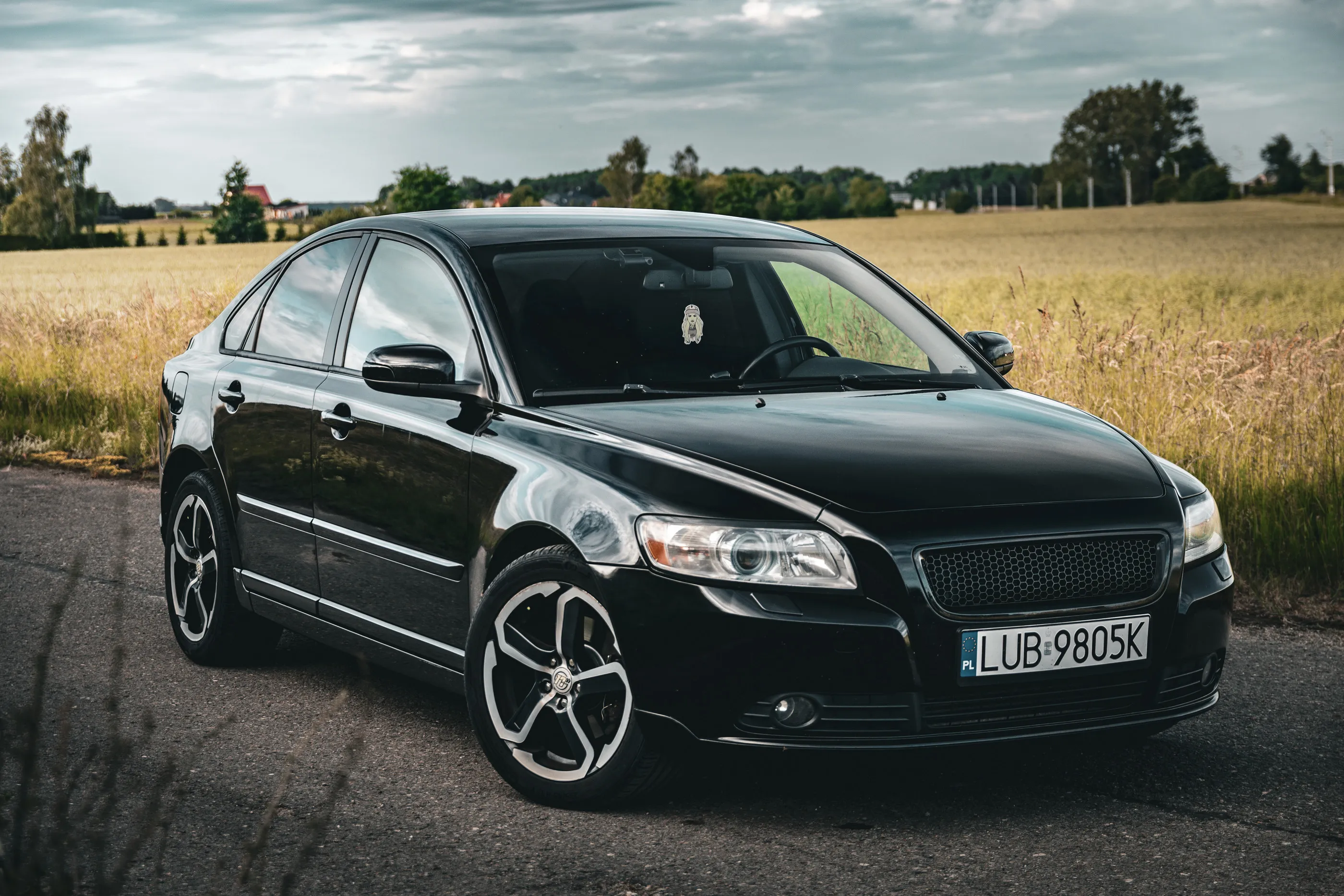 Czarne Volvo na drodze przy polu zboża