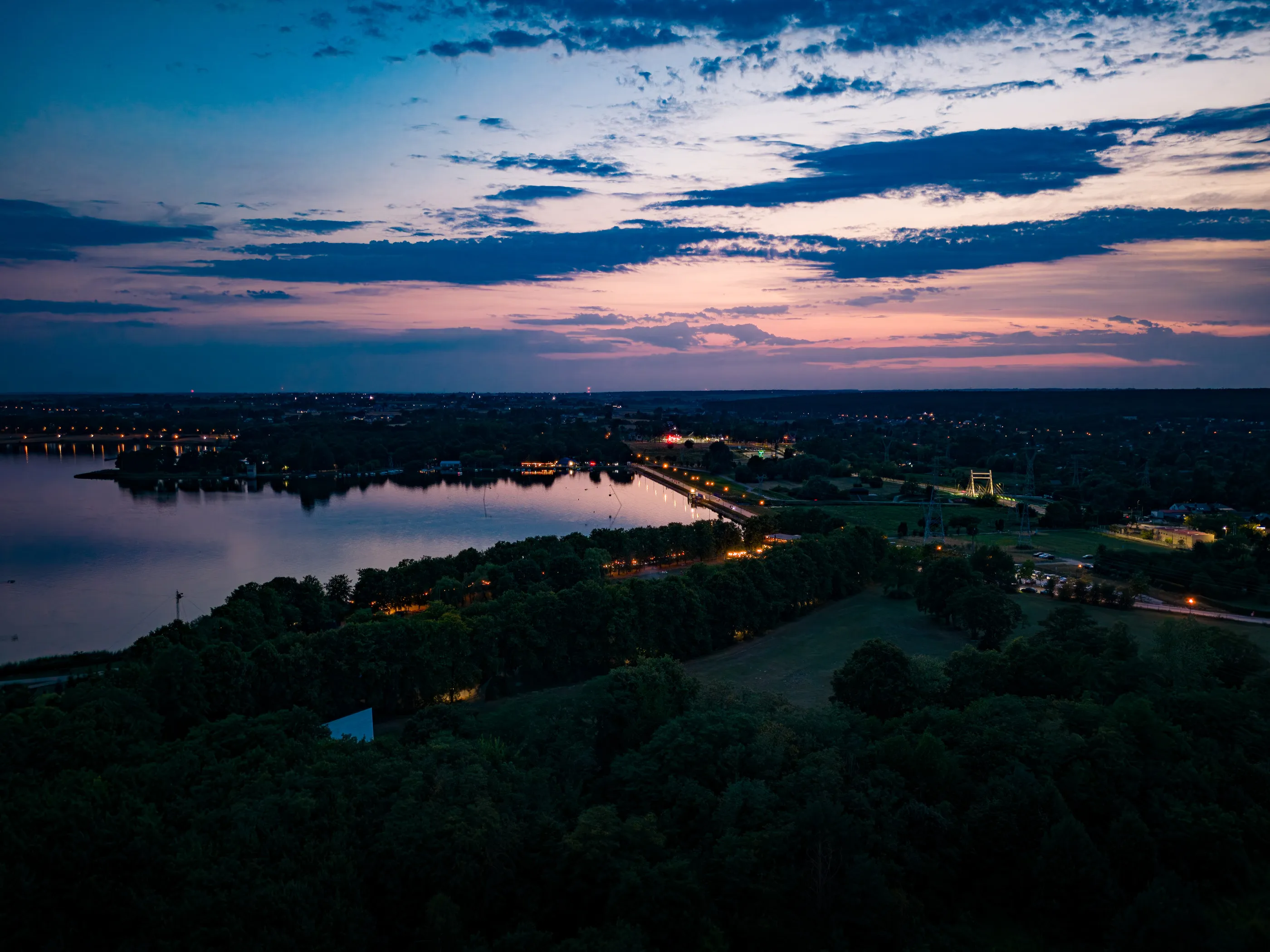 Jezioro i światła nad brzegiem o zmierzchu, widok z drona